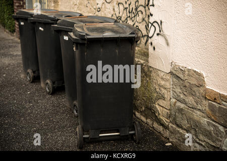 Vier schwarze Abfalleimer Mülleimer auf dem Bürgersteig Stockfoto