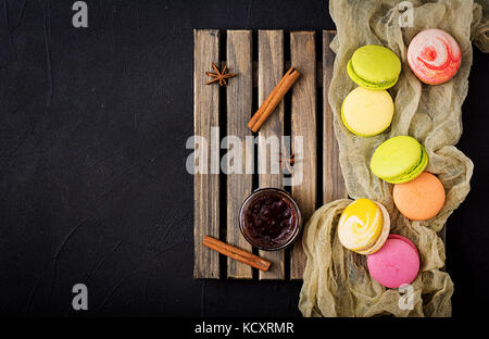 Bunte Makronen und einen Krug Honig auf einer hölzernen Hintergrund. Flach. top View Stockfoto