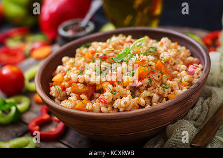 Vegetarische krümelig Graupen Porridge mit Gemüse in einen dunklen Hintergrund Stockfoto