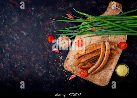 Gegrillte Würstchen auf dunklem Hintergrund. Oktoberfest. Flach. top View Stockfoto