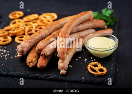 Brezeln und gegrillten Würstchen auf dunklem Hintergrund. Oktoberfest. Stockfoto