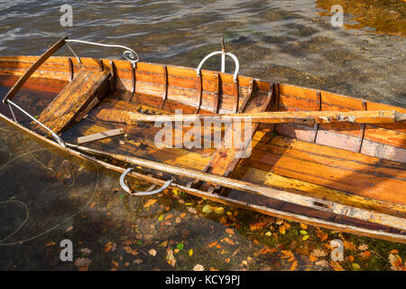 Teilweise eingetaucht hölzernen Ruderboot mit Herbstlaub, Keswick, Cumbria, England, Großbritannien Stockfoto