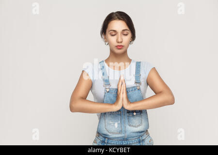 Schöne junge Kaukasier Weiblich, Holding hands in Namaste oder Gebet, halten die Augen geschlossen beim Üben von Yoga und Meditation zu Hause alleine. Studio