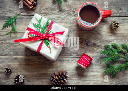 Weihnachten Hintergrund mit heißer Schokolade, Geschenkbox, Tannenzweigen und Kegel auf Holztisch. dekoriert Weihnachten und Winter Hintergrund. Stockfoto