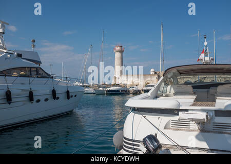 Boote im Hafen von Port Vauban, Leuchtturm im Hintergrund, Antibes, Cote d'Azur, Provence-Alpes-Cote d'Azur, Frankreich. Stockfoto