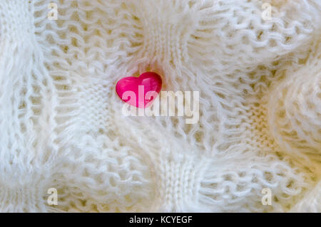 Pinki Herz auf einen gestrickten weißen Stoff Hintergrund Stockfoto