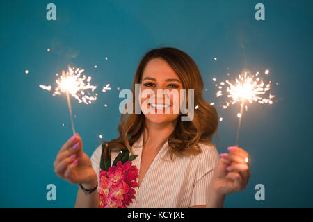 Portrait eines glücklichen Frau mit bengalischen Lichter über blauen Hintergrund. Weihnachten, Feste und Feiertage Konzept Stockfoto