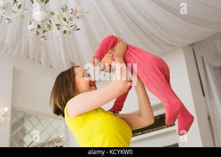 Glückliche Familie. Mutter wirft durcheinander Rennen Baby, zu Hause spielen Stockfoto