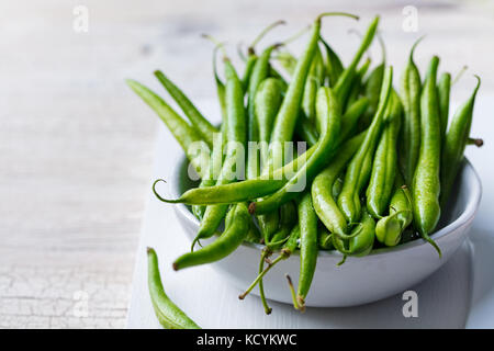 Grüne Bohnen in Weiß Schüssel auf Schneidebrett Stockfoto