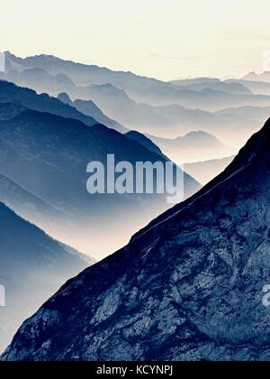 Einen spektakulären Blick auf die Berge Silhouetten und nebligen Täler. misty Erwachen der schönen Fee Tal. Gipfel der Felsen cremige Nebel Wolken schneiden. Stockfoto