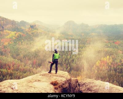 Der Mensch nimmt Fotos mit Smart Phone auf Höchststand von Rock Empire. verträumte farbenfrohe Natur mit herbstlichen orange rosa Nebel in einem schönen Tal der Rocky mountai Stockfoto