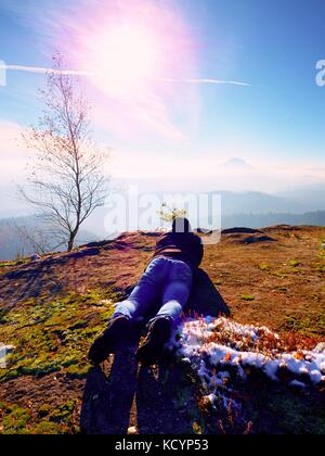 Mann legt und unter Foto von Spiegel Kamera am Hals. Snowy felsigen Gipfel des Berges. professioneller Fotograf nimmt Fotos mit Spiegel Kamera auf Pe Stockfoto