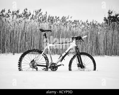 Das Mountainbike Aufenthalt im Schnee. verloren weg in tiefe Schneeverwehungen. Schnee schmilzt auf dunklen off road Reifen. Winter in das Feld ein. Stockfoto