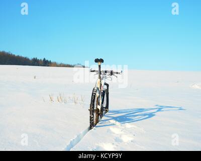 Mountainbike Urlaub im Pulverschnee. verloren weg in tiefe Schneeverwehungen. Hinterrad detail. Schneeflocken schmelzen in dunklen off road Reifen. Winterwetter in den Stockfoto