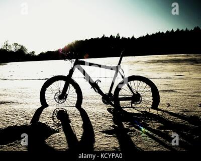 Extremme Kontrast. Mountainbike Aufenthalt im Pulverschnee. verloren weg in tiefe Schneeverwehungen. Hinterrad detail. Schneeflocken schmelzen in dunklen off road Reifen.Win Stockfoto