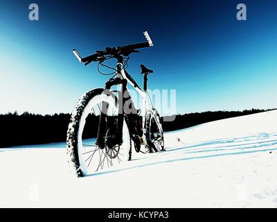 Extremme Kontrast. Mountainbike Aufenthalt im Pulverschnee. verloren weg in tiefe Schneeverwehungen. Hinterrad detail. Schneeflocken schmelzen in dunklen off road Reifen.Win Stockfoto