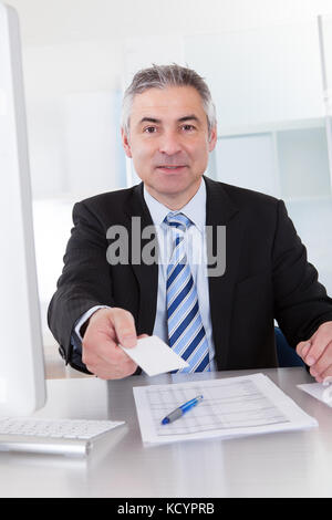 Senior Business mann Angebot Visitenkarte am Schreibtisch im Büro Stockfoto