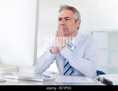 Portrait von Reifen Geschäftsmann Denken am Schreibtisch im Büro Stockfoto