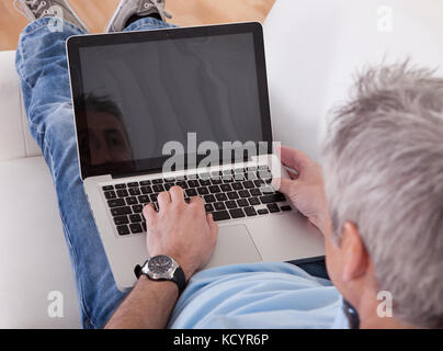 Portrait von Happy Reife mit Laptop auf der Couch Mann Stockfoto