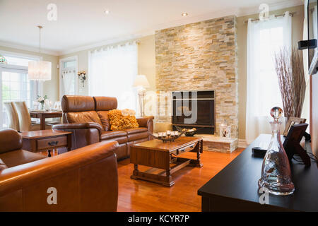 Braunen Ledersofas mit hölzernen Couchtisch und Holzofen Kamin mit