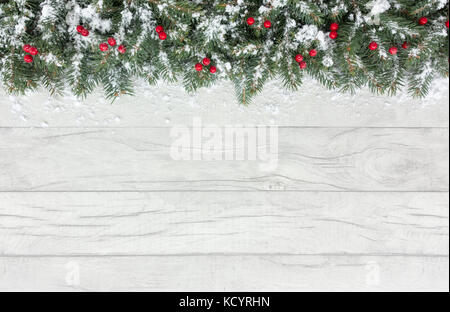 Weihnachten Grenze aus natürlichen Weihnachtsbaum tanne Zweige und roten Beeren auf einem grauen Hintergrund aus Holz im Schnee mit Kopie Raum abgedeckt. Stockfoto