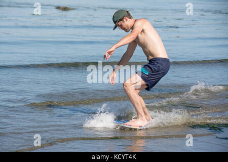 Junger Mann skim Boarding am Strand von Sidney Island, British Columbia, Kanada Stockfoto