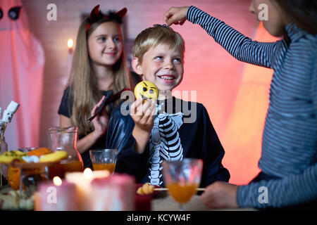 Portrait von Kindern tragen Halloween Kostüme spielen in eingerichtete Zimmer während der Party, Mädchen, Spielzeug Spinne auf der Oberseite des niedlichen kleinen Jungen Kopf Stockfoto