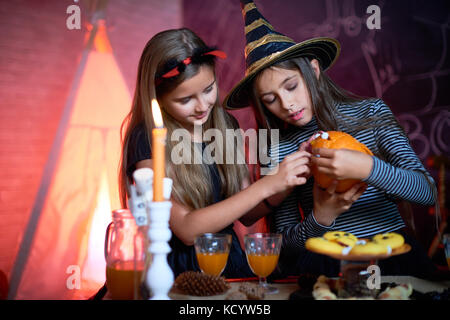 Portrait von zwei kleinen Mädchen, Halloween Kostüme, geschnitzten Kürbis in eingerichtete Zimmer Stockfoto