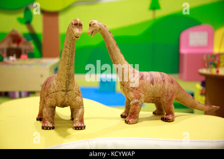 Zwei leistungsstarke Spielzeug Dinosaurier sprechen glücklich in der Kinderspielplatz. Stockfoto