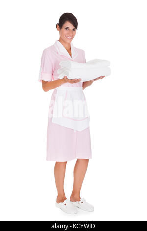 Gerne weibliche maid Holding der weißen Handtücher über weißen Hintergrund Stapel Stockfoto