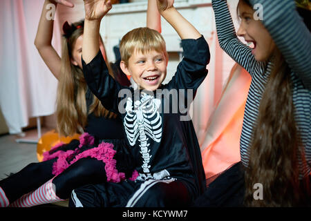 Portrait von lächelnden kleinen Jungen tragen Skelett Kostüm Spaß während Halloween Feiern mit Freunden zu Hause. Stockfoto