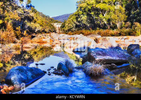 Eis bedeckt noch Wasser auf Snowy River unter snowy Hydro Power Generation Damm zwischen immergrünen gumtree Holz hoch in den verschneiten Bergen im Winter. Stockfoto