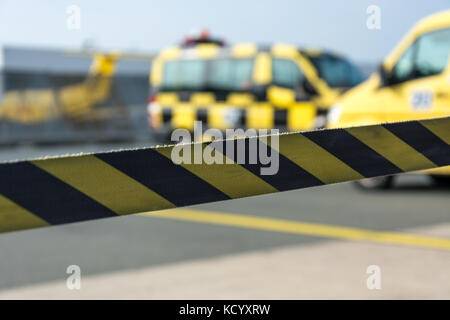 Schwarze und Gelbe absperrband am Flughafen mit Autos im Hintergrund Stockfoto