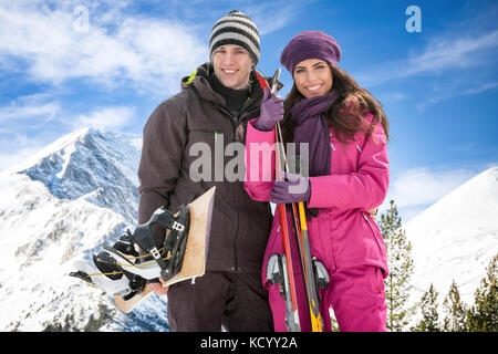 Porträt eines Mannes und einer Frau lächelnd mit Skiern im Schnee. Stockfoto