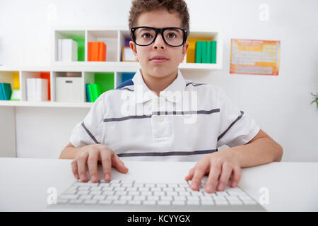 Kleiner Junge mit Brille mit Computer Tastatur, Kind am Computer suchen Stockfoto