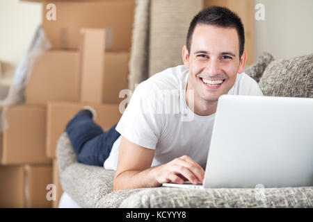 Glücklich, junger Mann mit Laptop in seinem neuen Zuhause Stockfoto