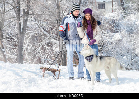 Junges Paar mit seinem Hund im verschneiten Wald Stockfoto