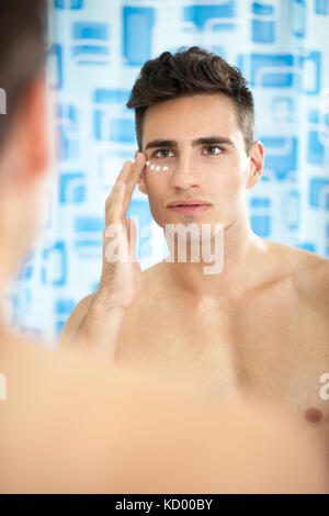 Schöner mann Anwendung Creme auf seinem Gesicht in Bad Stockfoto