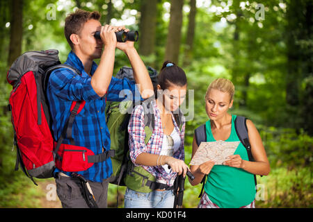 Wanderer Gruppe Mann durch ein Fernglas und Mädchen lesen Karte suchen Stockfoto