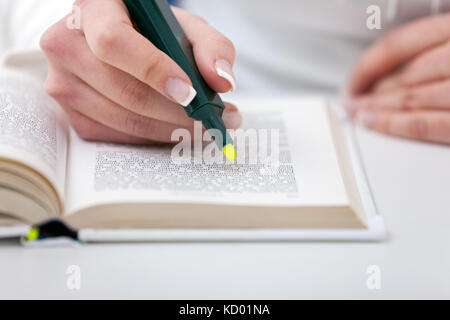 Textmarker in weiblicher Hand markierten Text im Buch, Bildung Konzept Stockfoto