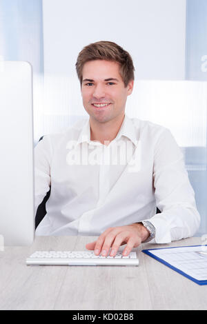 Portrait der junge Unternehmer mit Computer am Schreibtisch Stockfoto
