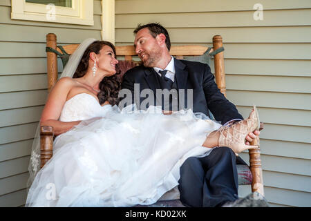 Brautpaar sitzen in einem Schaukelstuhl und tragen Ihre tuxedo Wedding Dress. Stockfoto