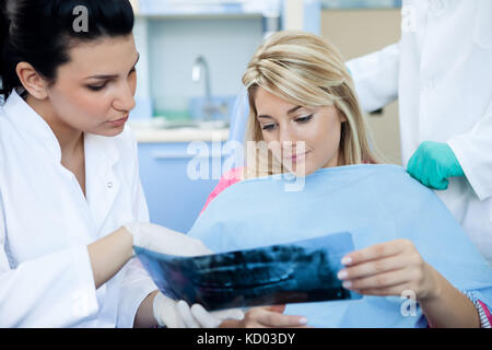 Weibliche Zahnarzt und Patient im Untersuchungsraum betrachten eine zahnmedizinische Röntgensysteme. der Zahnarzt zeigt auf der x-ray. Stockfoto