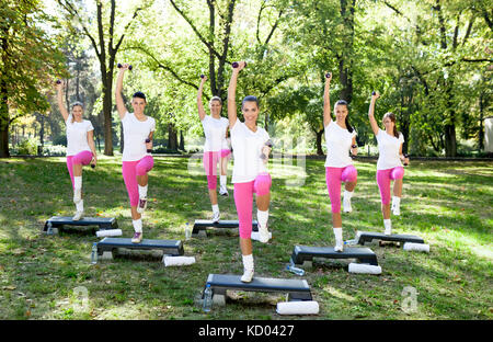 Energetische Gruppe von jungen Frauen, Fitness Übungen im Freien an einem sonnigen Tag Stockfoto