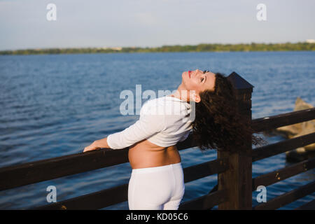 Junge schwangere Yoga im Freien. schwanger Yoga. Frauen, verschiedene Übungen. Fluss auf Hintergrund. Konzept der gesunden Lebensweise und Relaxa Stockfoto