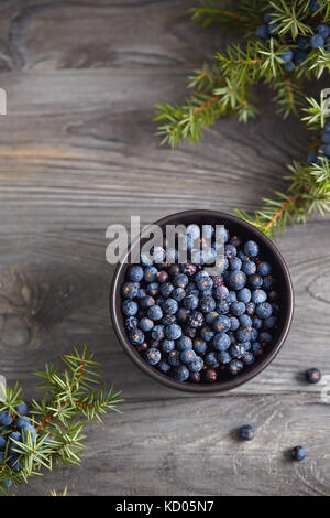 Kleine Schüssel mit Wacholdersamen auf Holztisch. Stockfoto