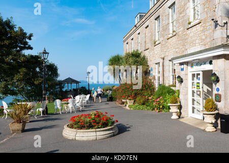 Haupteingang des Berry Head Hotel, Brixham Torbay, Devon. Blick in die Bucht und mit zwei Personen auf der Terrasse in der Ferne. Sommer Stockfoto