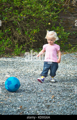 Ein kleines Mädchen 2 bis 3 Jahre alten Treten eines Fußball Stockfoto