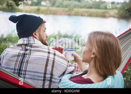 Ansicht der Rückseite des Paares in der Hängematte holding Emaille Becher, Krakow, Malopolskie, Polen, Europa Stockfoto