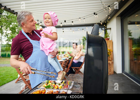 Reifer Mann mit Kleinkind Enkelin Grillen bei Familie Mittagessen auf der Terrasse Stockfoto